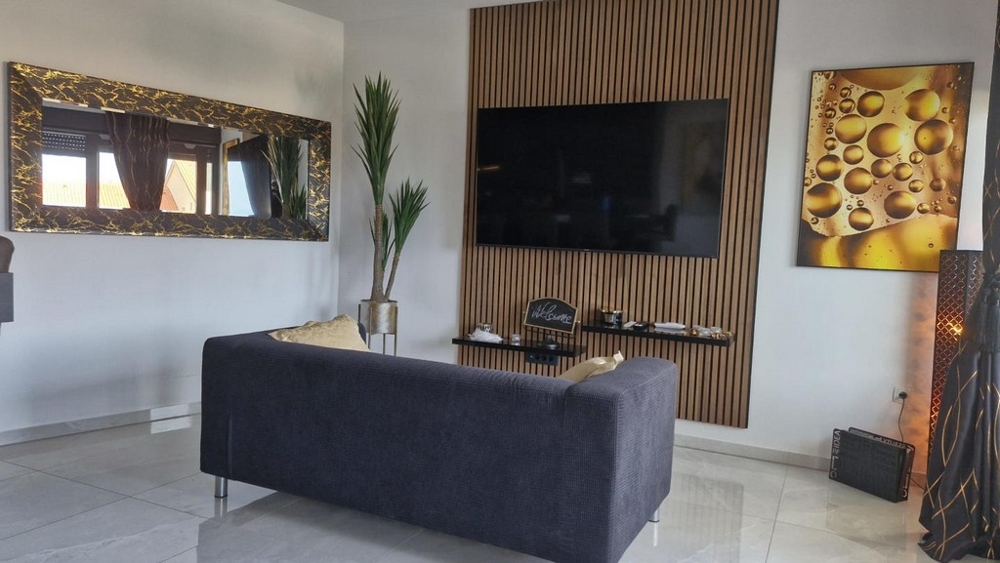 Vardagsrum med stor TV, soffa och dekorativa element