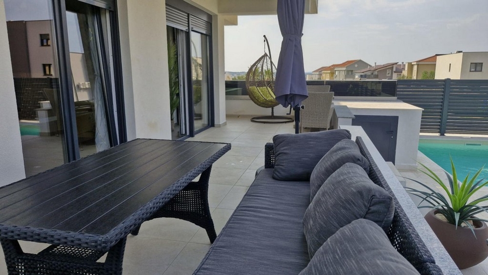 Möblerad trädgård och pool av semesterlägenhet A3413, som är till salu i Kroatien i Novalja.