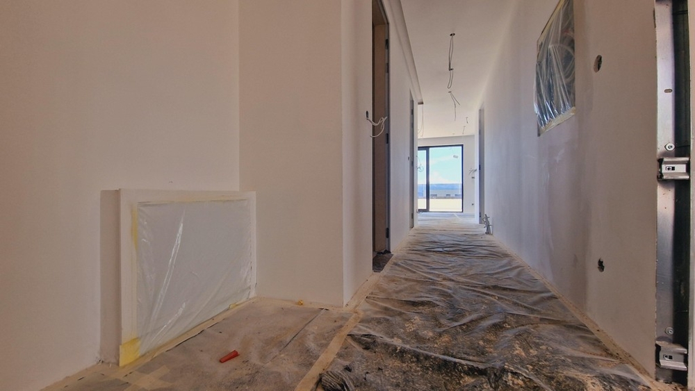 Nybyggnadens hall i byggskede med utsikt över terrassen i slutet av korridoren.