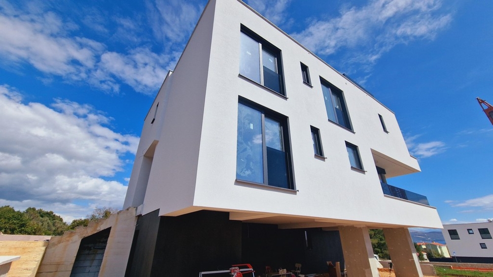 Exteriör vy av den moderna nybyggnaden med tydlig, vit fasad och flera stora fönster.