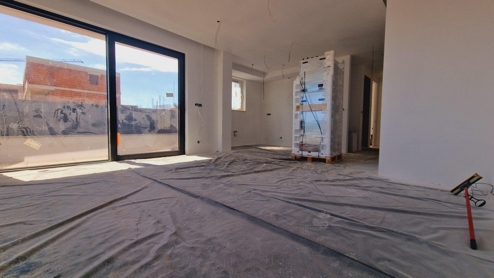 Invändig vy av den nya lägenheten med stora fönsterfronter och fri sikt över terrassen och omgivningen.