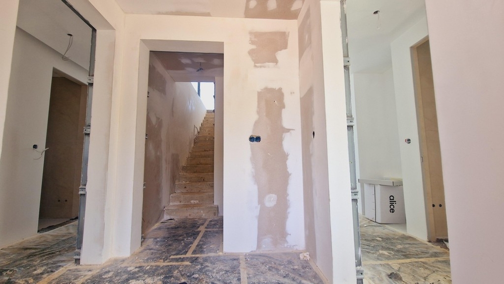 Trappa och hall under uppbyggnad med synliga skalväggar och öppna kablar.