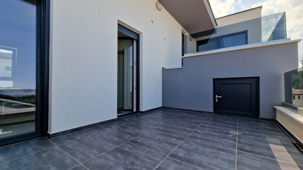 Modern altan med grått kakel, glasräcken och tillgång till lägenheten.