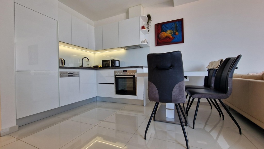 Rymligt öppet kök med matplats och modern utrustning inklusive inbyggda vitvaror.