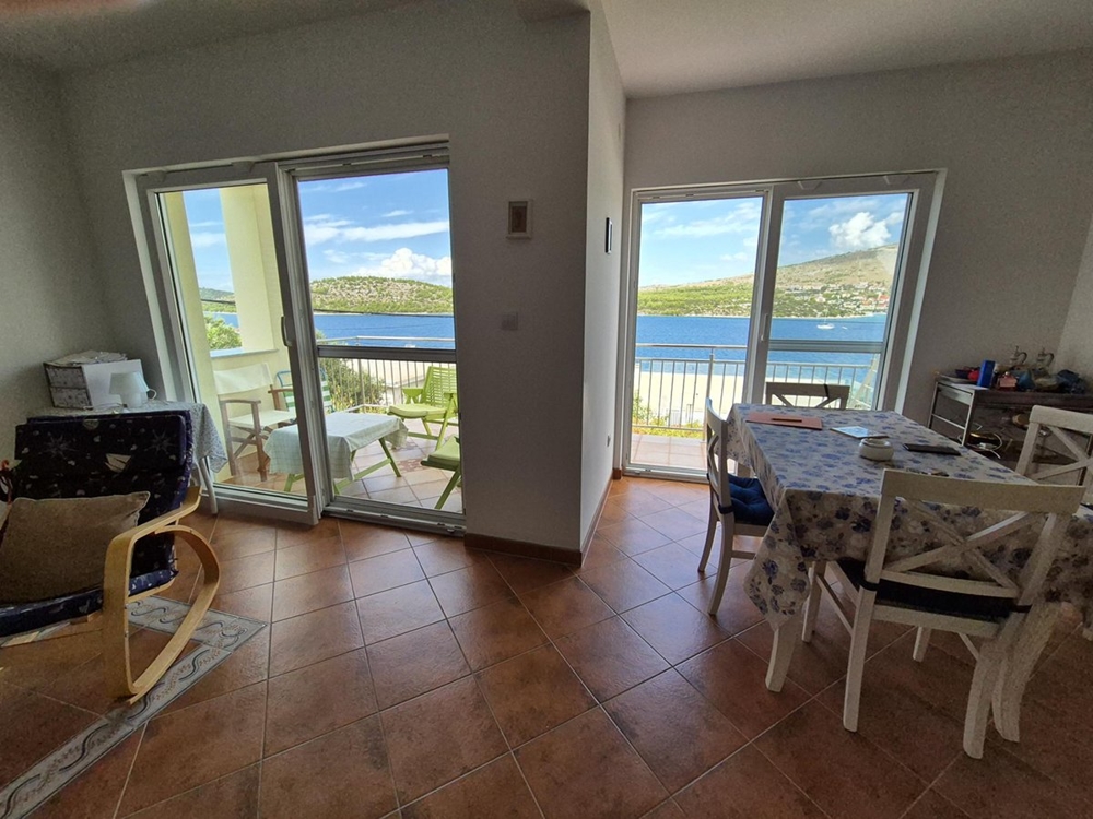 Ett vardagsrum med en stor skjutbar glasenhet som vetter mot en terrass med havsutsikt.