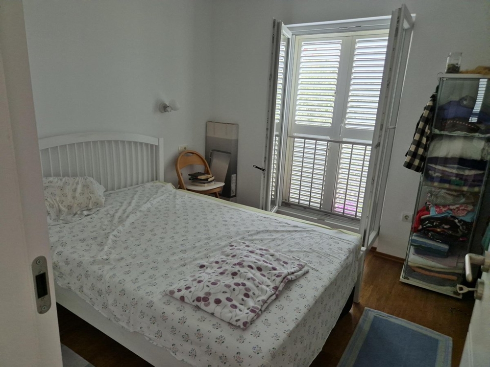 Ett sovrum med dubbelsäng, vita möbler och ett fönster