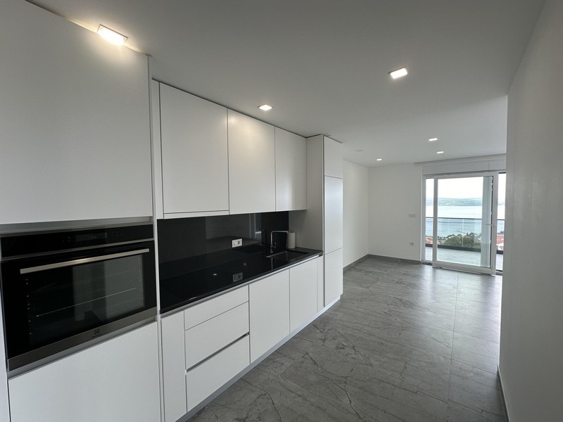 Modernt vitt kök med öppen planlösning och havsutsikt