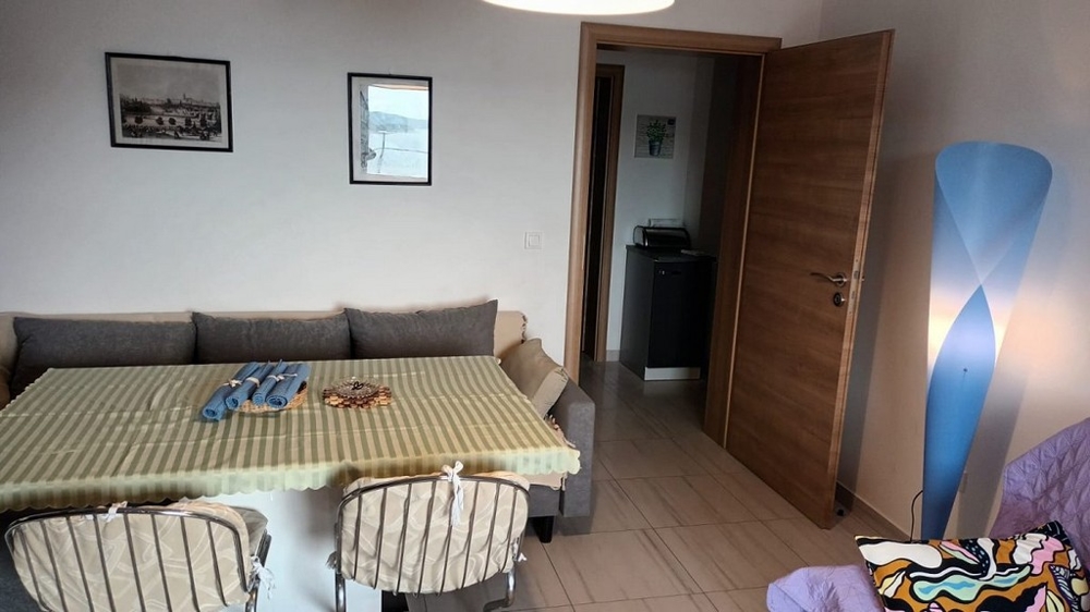 Matplats med matbord och stolar, bredvid en soffa, och öppen dörr till korridoren.