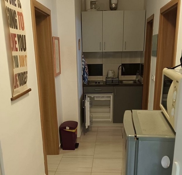 Litet kök med gråa skåp, minikyl och mikro i hallen.