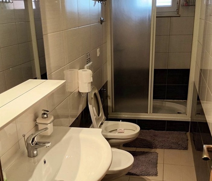 Badrum med dusch, toalett, bidé och handfat, modernt kaklat.