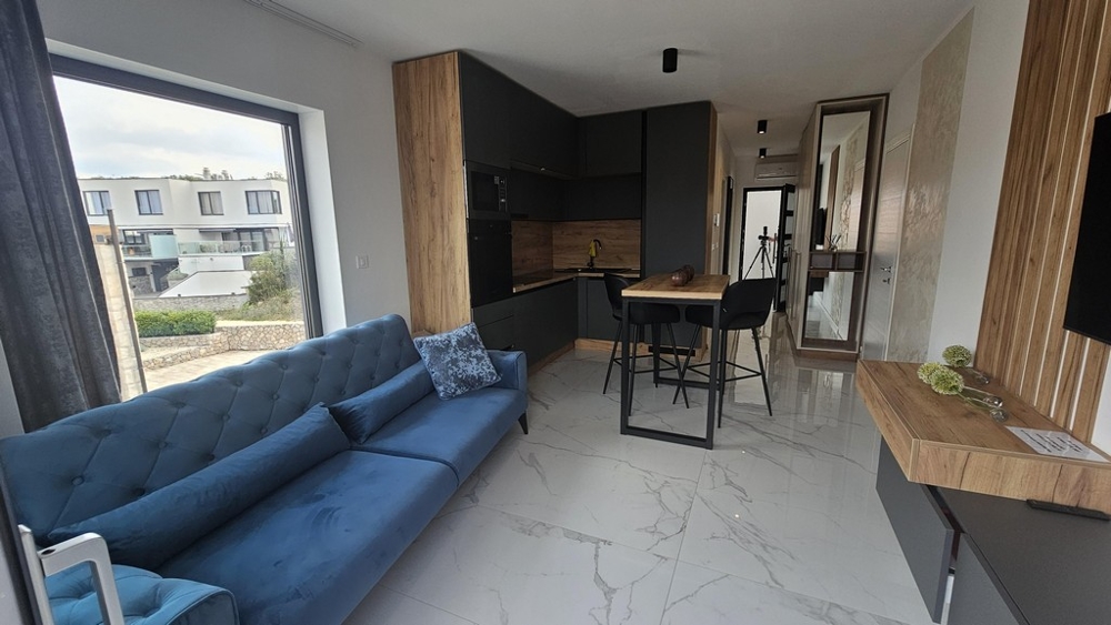 Vardagsrum med soffa, angränsande kök och balkong