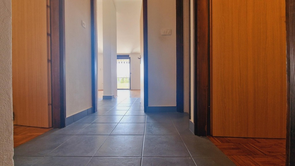 Hall med klinkergolv, dörrar till sovrum och vardagsrum.