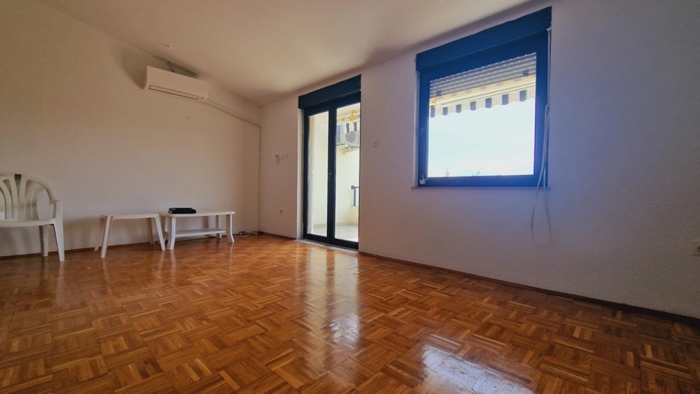 Ljust vardagsrum med parkettgolv, utgång till altan, stora fönsterpartier.