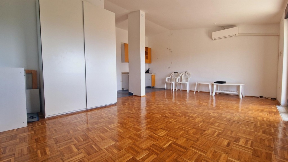 Rymligt vardagsrum med parkettgolv, luftkonditionering och minimalistisk inredning.