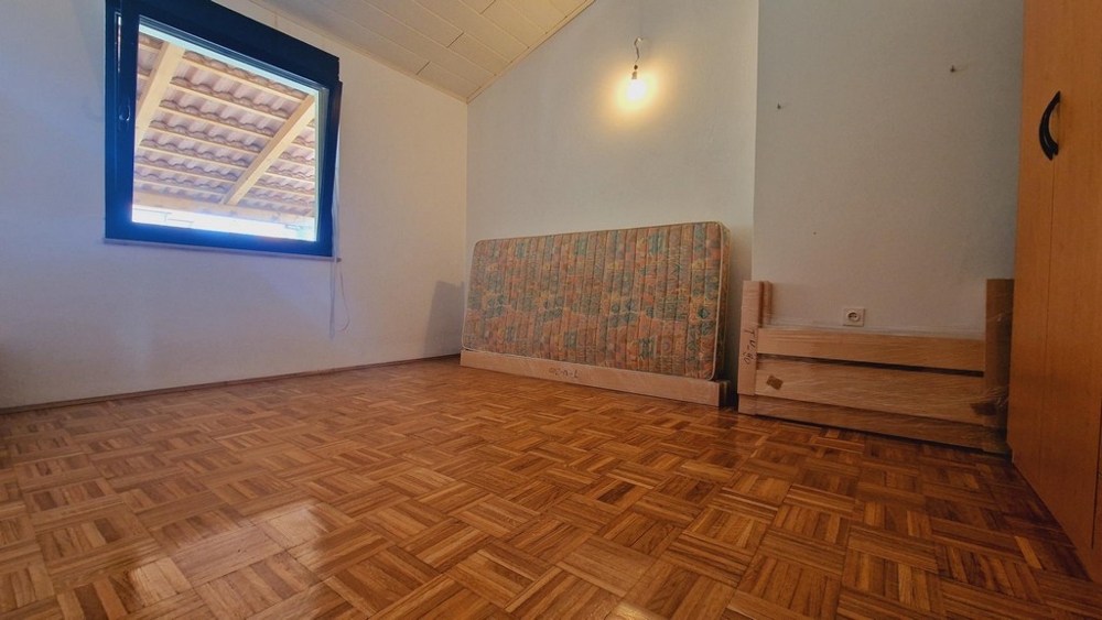 Sovrum med trägolv och fönster, delvis möblerat rum.