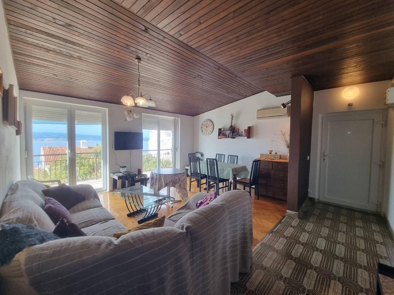 Vardagsrum med utgång till balkong, trätak och havsutsikt.
