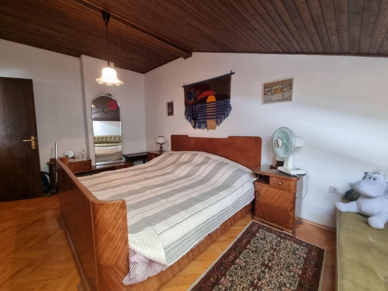 Sovrum med stor säng, trätak och heltäckningsmatta.