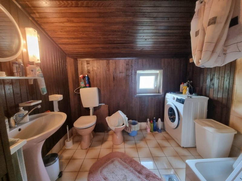 Badrum med mörk träpanel och tvättmaskin.