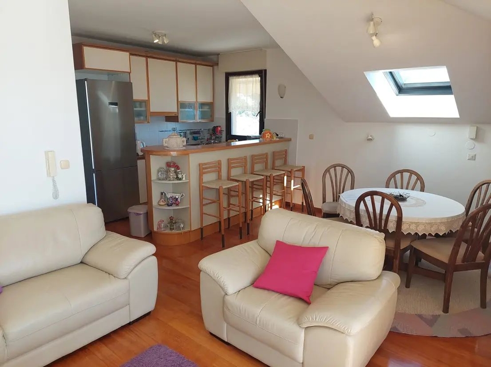 Mysigt vardagsrum med kök, bar och matbord i vindslägenhet