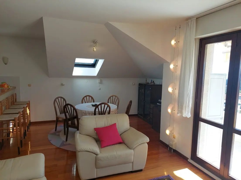 Matbord i vindslägenhet, stora fönster och barstolar vid köksbänken