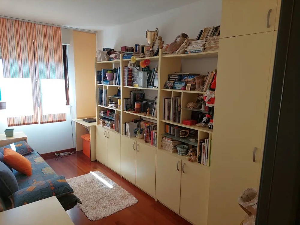 Rum med bokhyllor, skrivbord och soffa, ljusa fönster