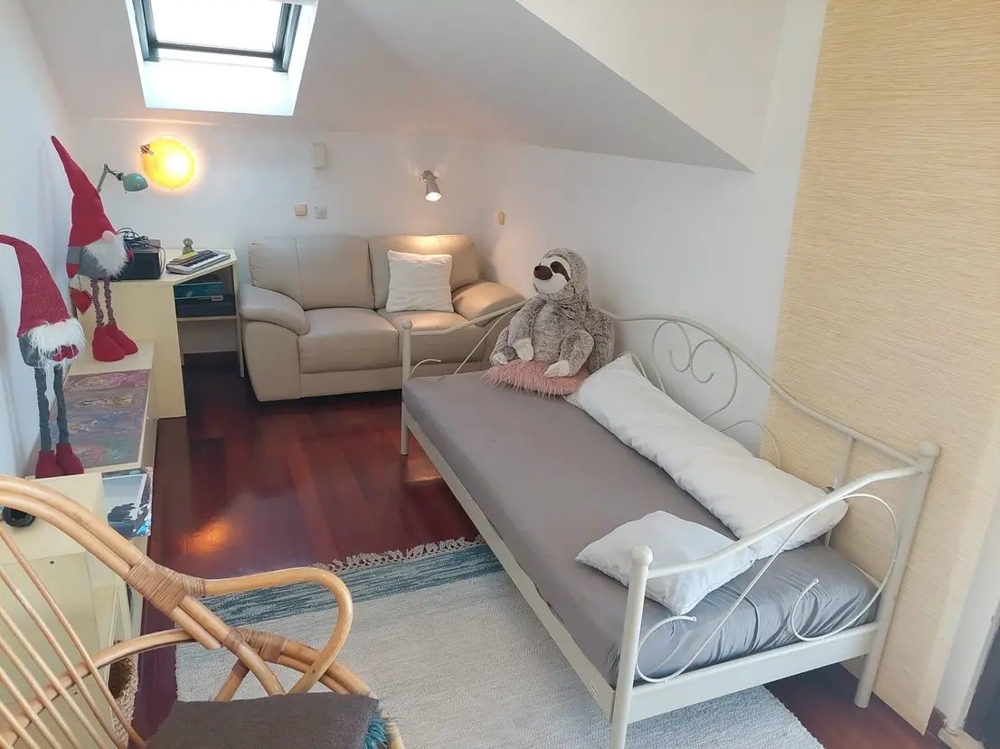 Rum med säng, soffa, takfönster och dekorationer, inklusive gosedjur