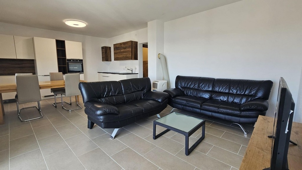 Möblerat vardagsrum och utsikt över köket i lägenhet A3475.