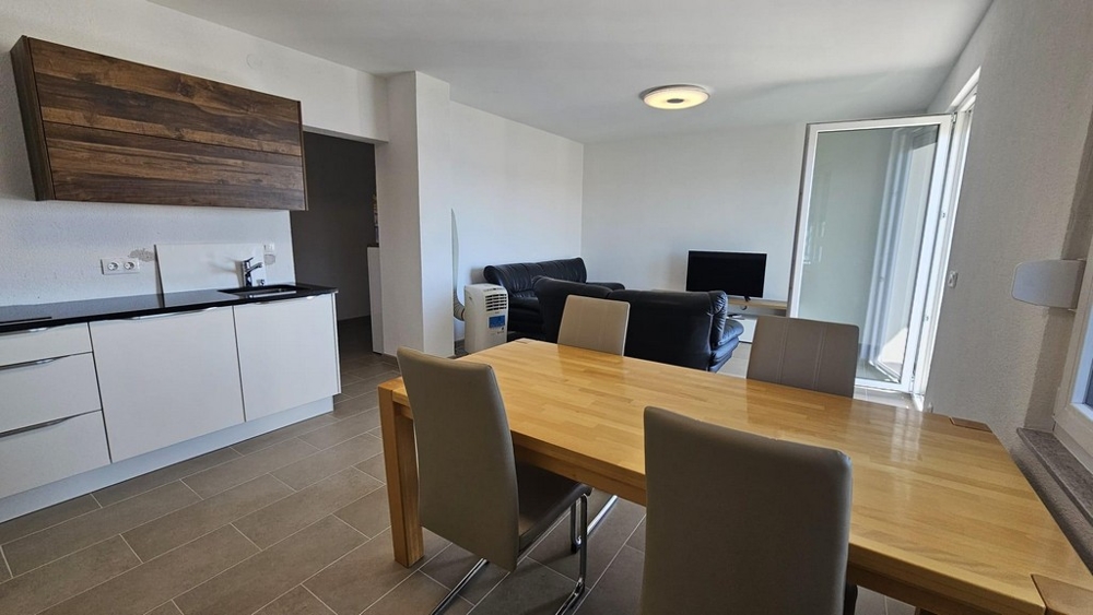 Modernt öppet kök med träelement, matplats och sittgrupp som leder till balkong.