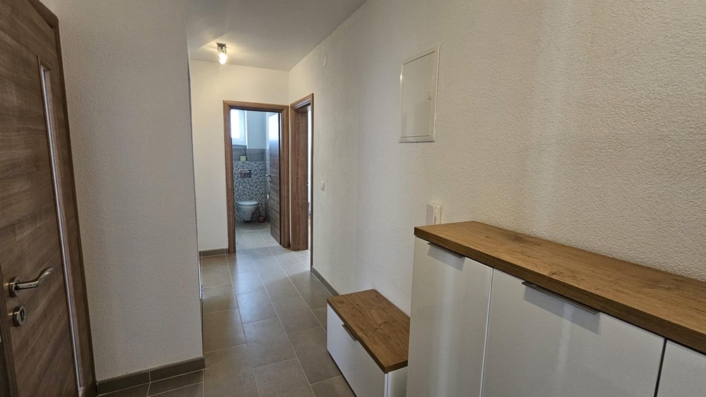 Hall som leder till badrum med klinkergolv och trädetaljer.