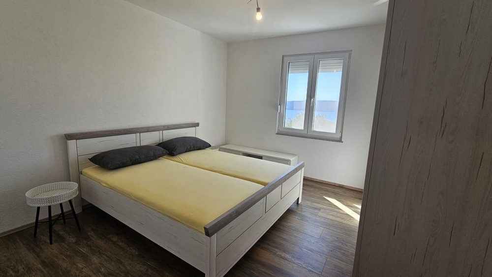 Sovrum med dubbelsäng och ett fönster med utsikt över havet.