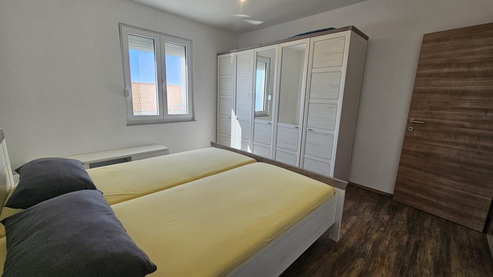 Rymligt sovrum med dubbelsäng, stor garderob och havsutsikt genom fönstret.