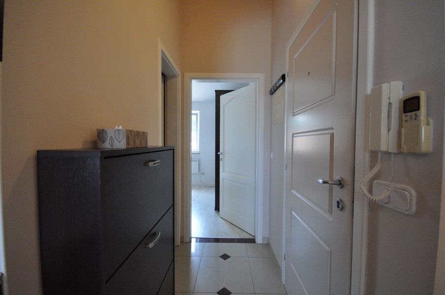 Hall med vit dörr, mörkt skåp och porttelefon på vägg, tillgång till olika rum