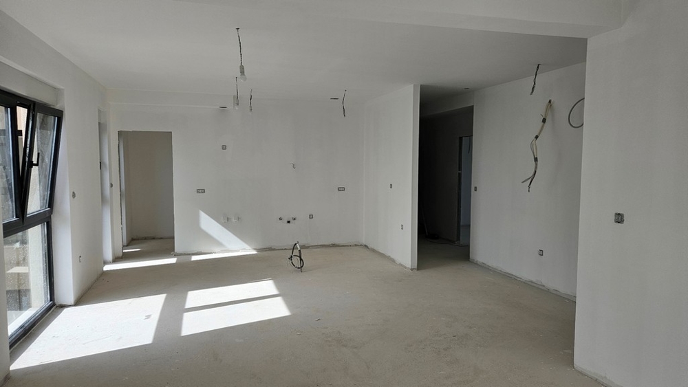 Oavslutat vardagsrum med öppna fönster och förberedda anslutningar för kök