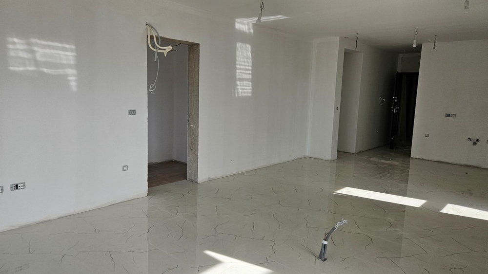 Oavslutat rum med ljusa golvplattor, redo för vidare inredningsarbete