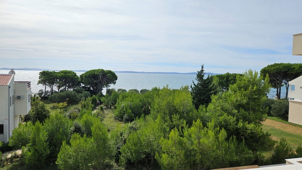 Havsutsikt från andra våningen omgiven av grön vegetation och träd