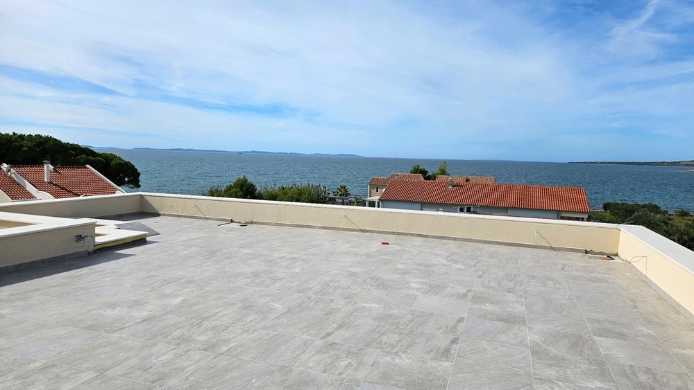 Takterrass med panoramautsikt över havet och röda tak på husen nedanför