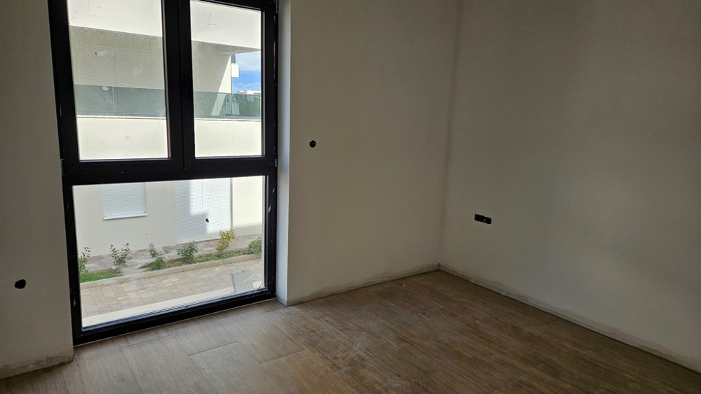 Ytterligare ett rum med stora fönster, utsikten visar en modern byggnad och en stenlagd yta.