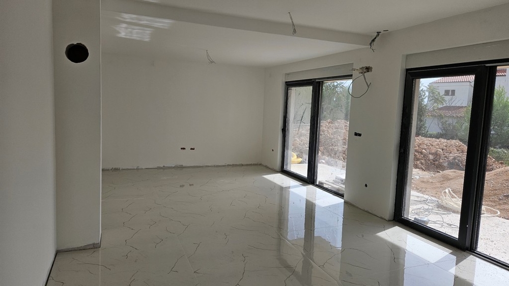 Inredning med stor fönsteryta, vita väggar och klinkergolv, fortfarande under uppbyggnad.