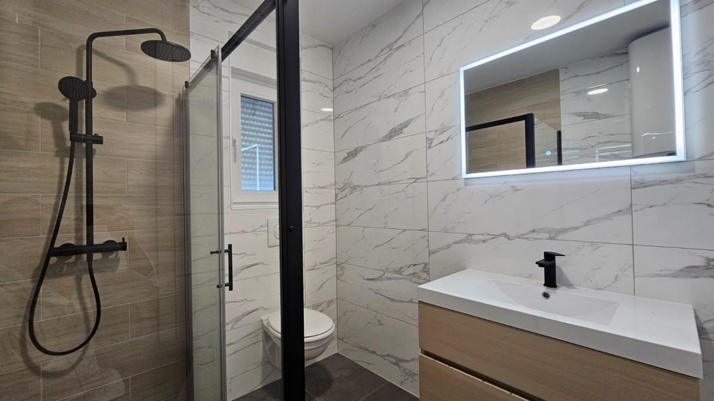 Modernt badrum med regndusch och spegel