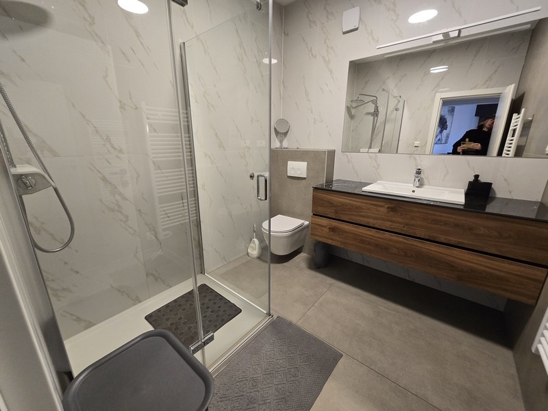 Rymligt badrum med dusch, handfat och elegant kakel.