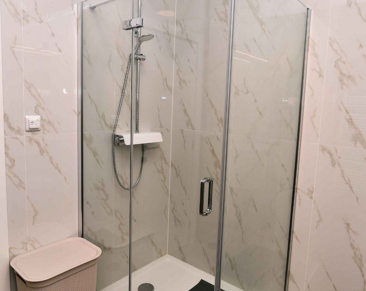 Dusch med glasdörrar och modern kran i högkvalitativ lägenhet.