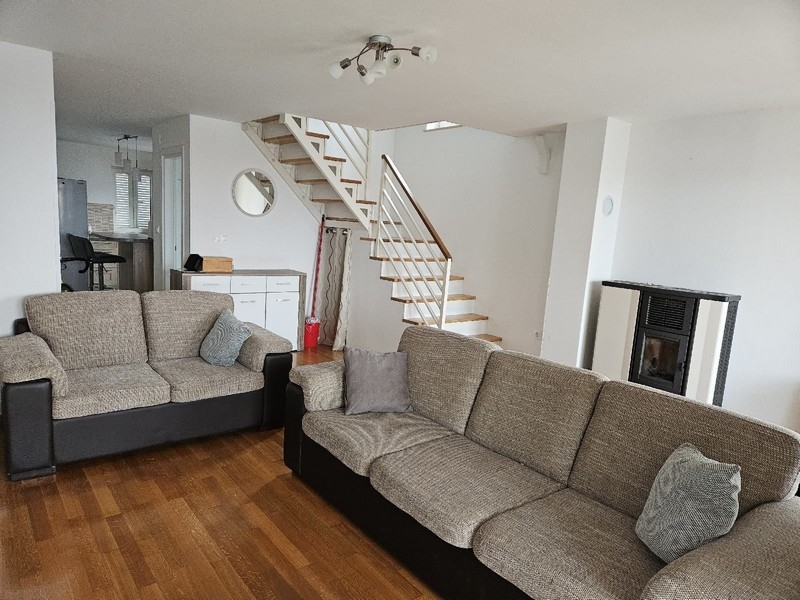 Vardagsrum med soffa, trappa och pelletskamin