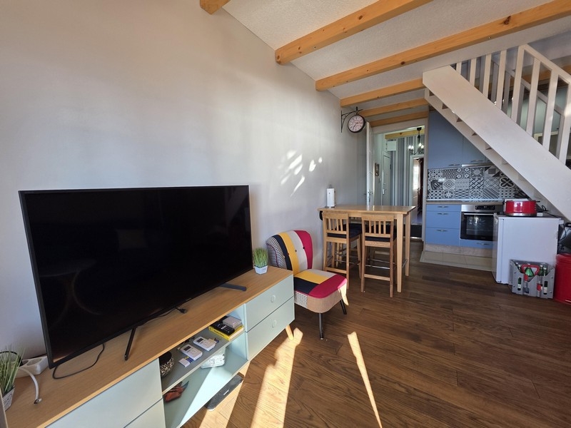 Vardagsrum med TV, matbord och öppet kök