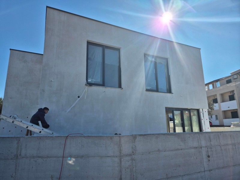 Exteriör vy av huset med stora fönster och solljus