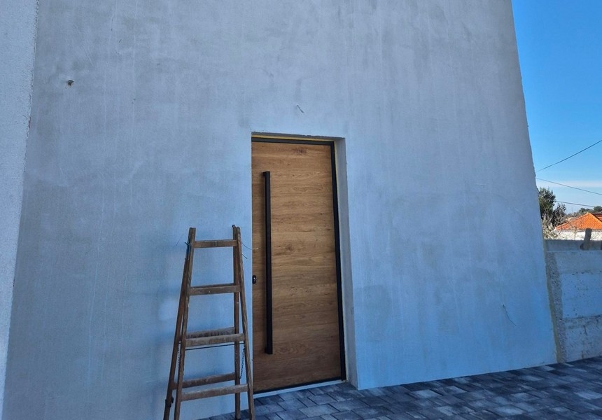 Modern entrédörr med trälook och stege på fasaden