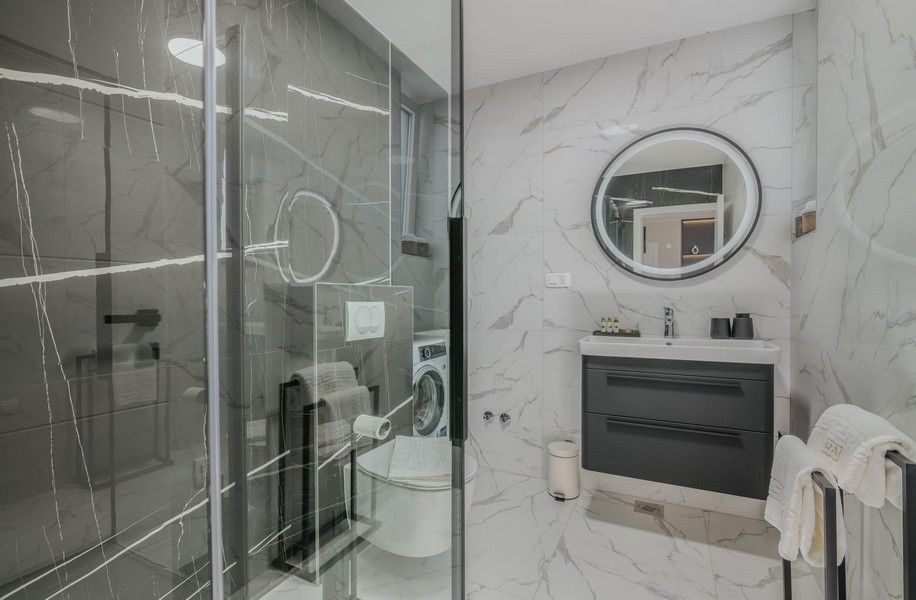 Badrum med modern glasdusch och marmorkakel