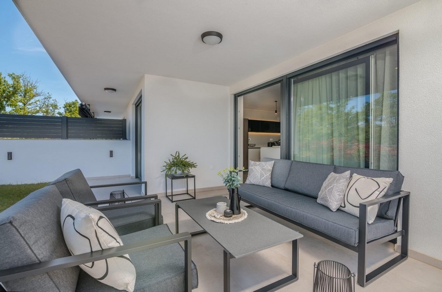 Täckt terrass med moderna sittplatser och utsikt över trädgården