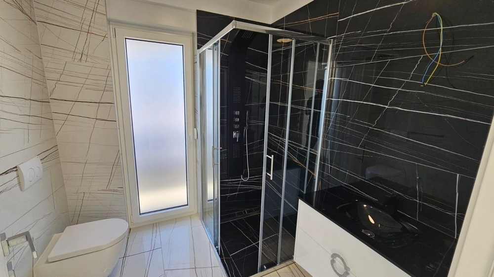 Stilrent badrum med dusch och mörkt kakel