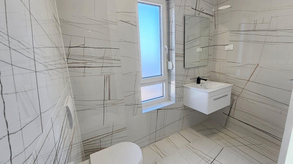 Modernt kaklat badrum med fönster, handfat och toalett