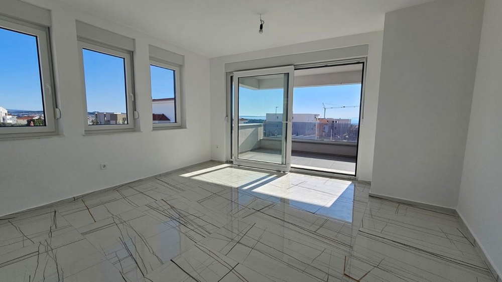 Ljust vardagsrum med balkong och havsutsikt.